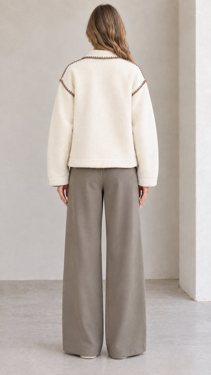 Back view of model wearing cream fleece jacket with decorative shoulder trim