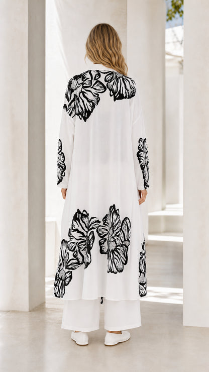 Back full view of women's white floral print longline shirt and wide-leg trousers