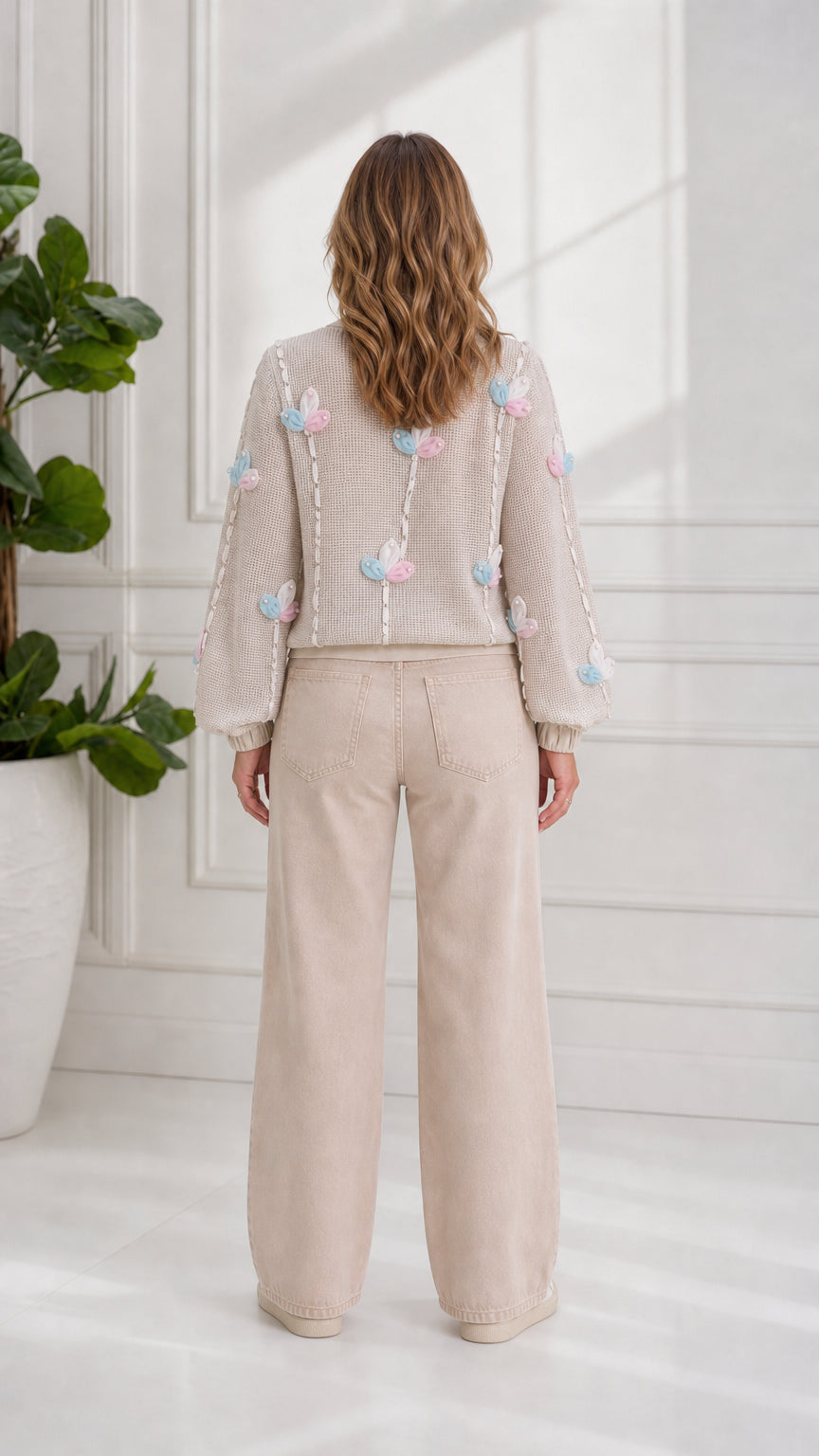 Back view of model showcasing floral appliqué details on beige zip cardigan