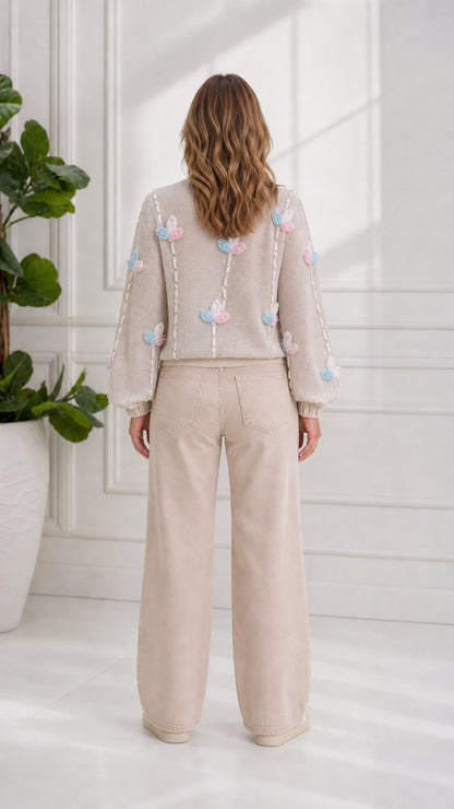 Back view of model showcasing floral appliqué details on beige zip cardigan