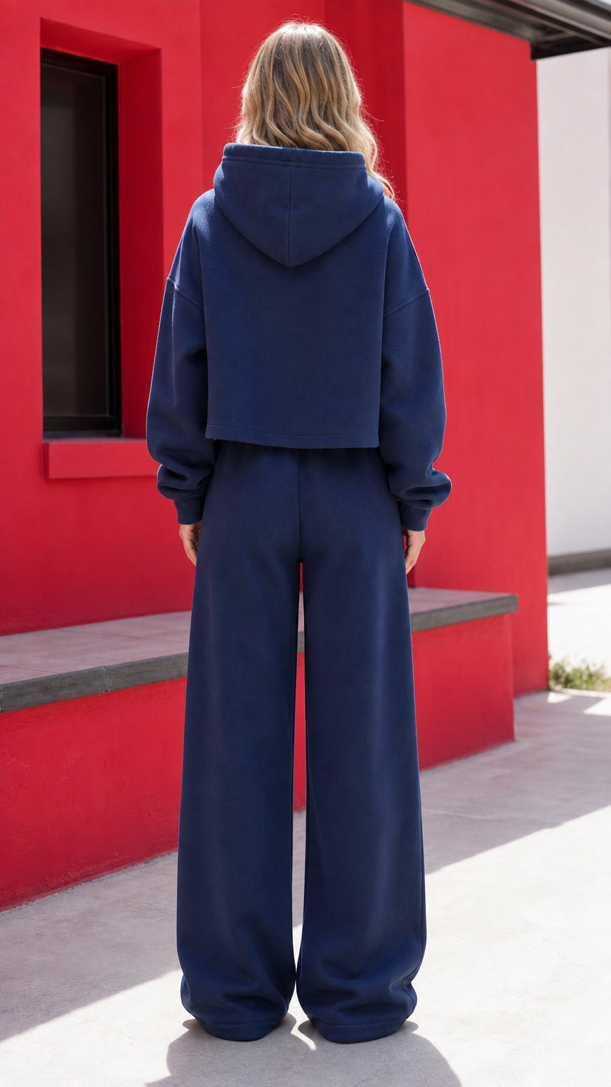 Back full-length view of woman wearing navy blue fleece hoodie and wide-leg pants