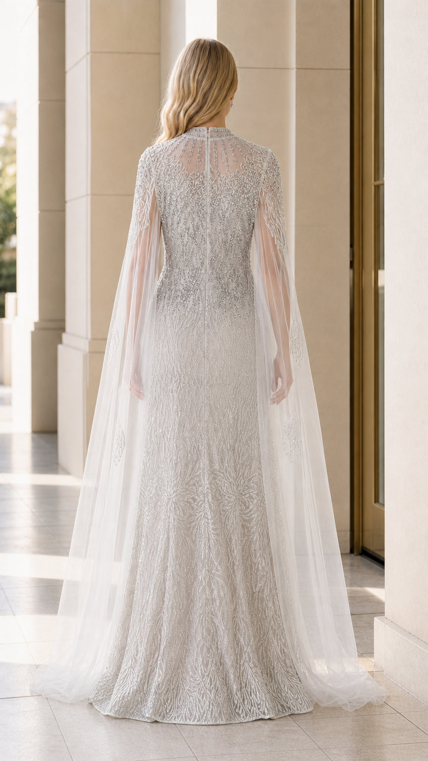 Back view of model in silver sequin formal dress with flowing tulle cape