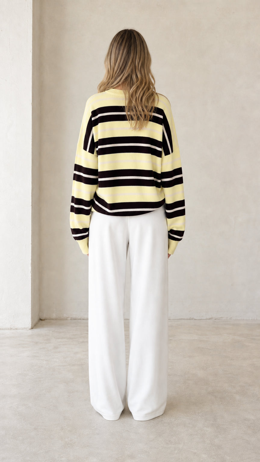 Back view of pale yellow striped crewneck knit sweater with relaxed fit
