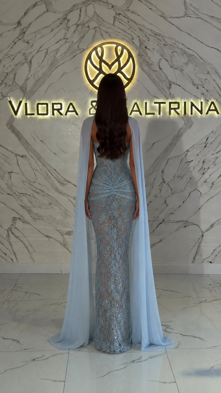 Back view showing light blue flowing sheer cape on formal dress