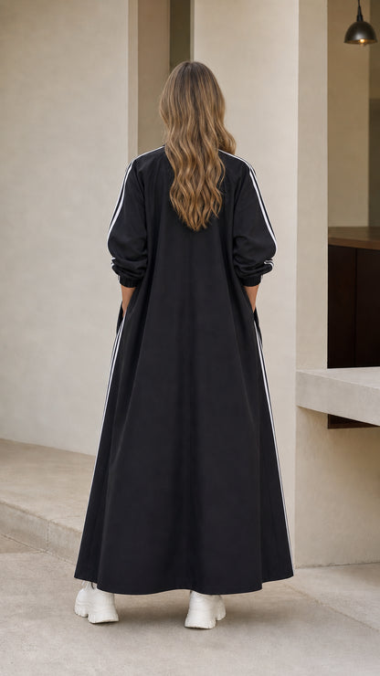 Back view of woman wearing full length black duster jacket with sleeve stripes