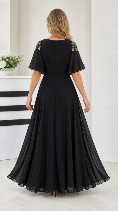 Back view of black flutter sleeve evening gown showing zipper and pleated skirt