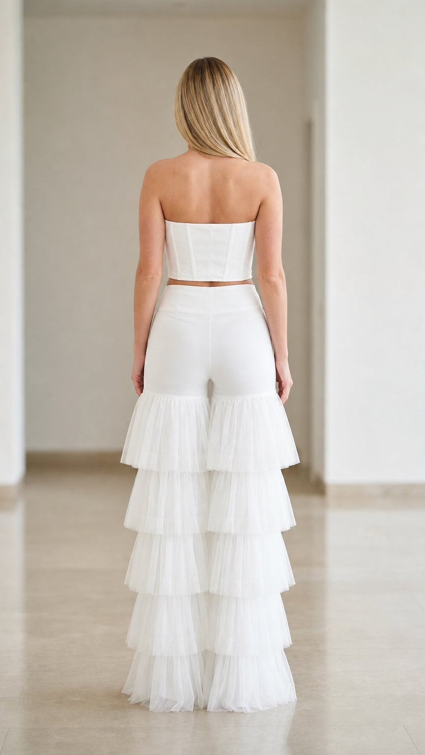 Back view of white strapless bustier crop top and high-waisted tiered ruffle pants