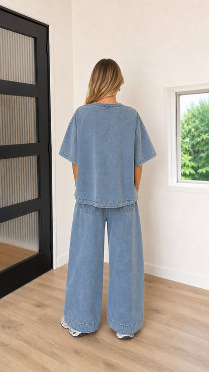 Back view of model wearing Washed Blue oversized drop-shoulder tee and wide-leg trousers