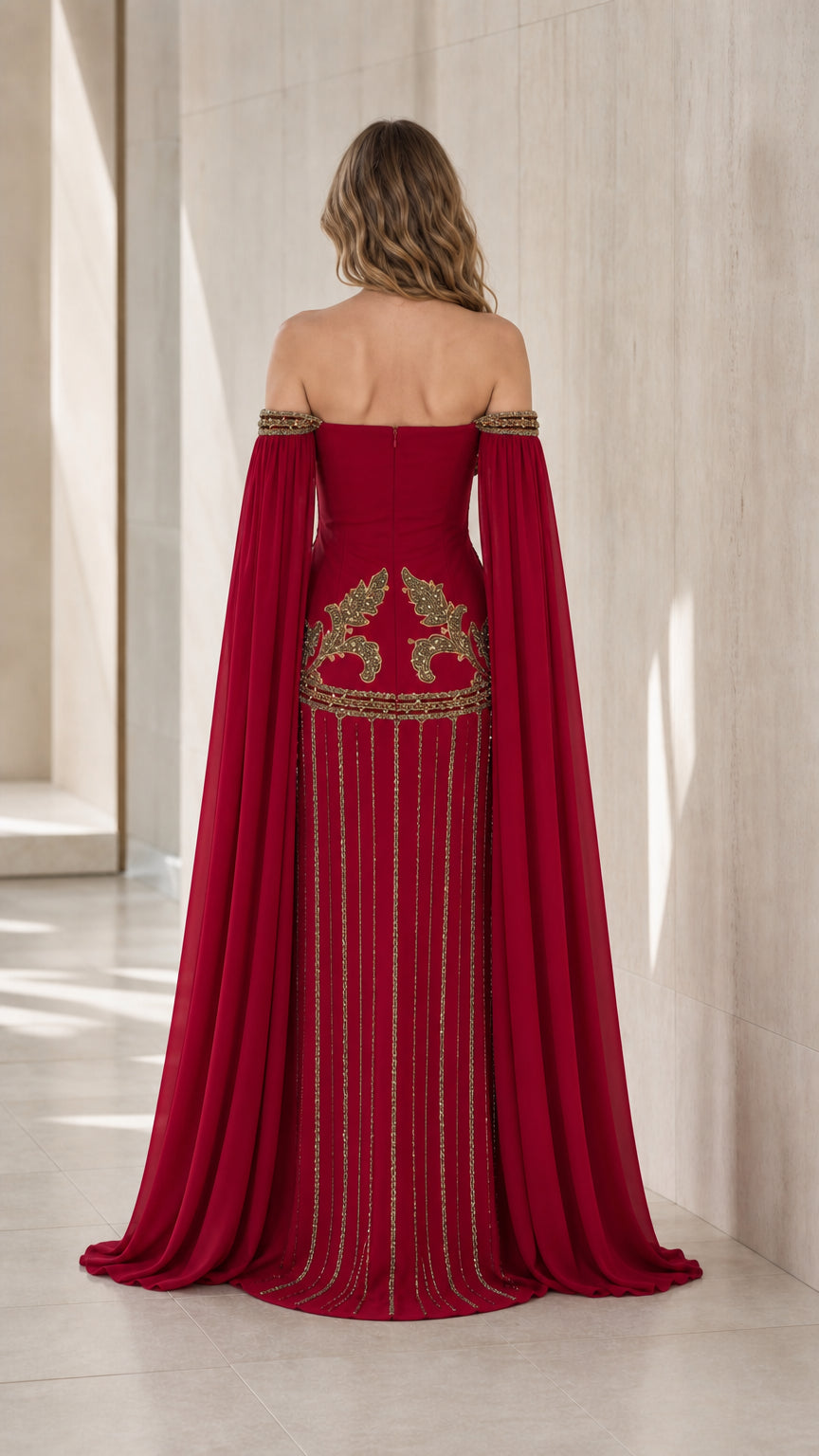 Back view of formal burgundy gown with gold embellished accents and dramatic cape sleeves
