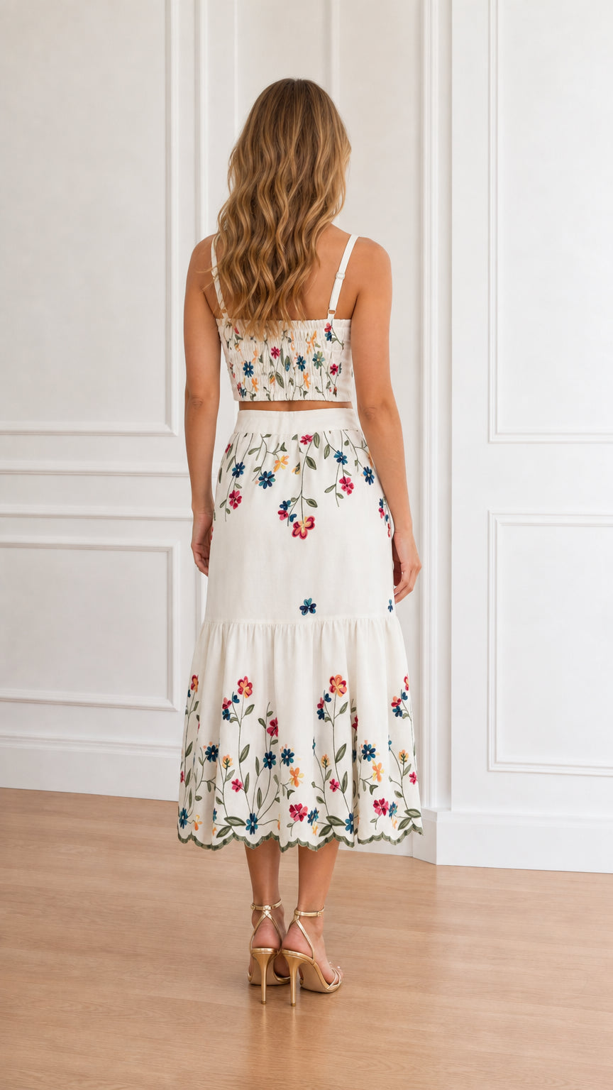 Back view of model wearing white sweetheart top with smocked back and tiered skirt