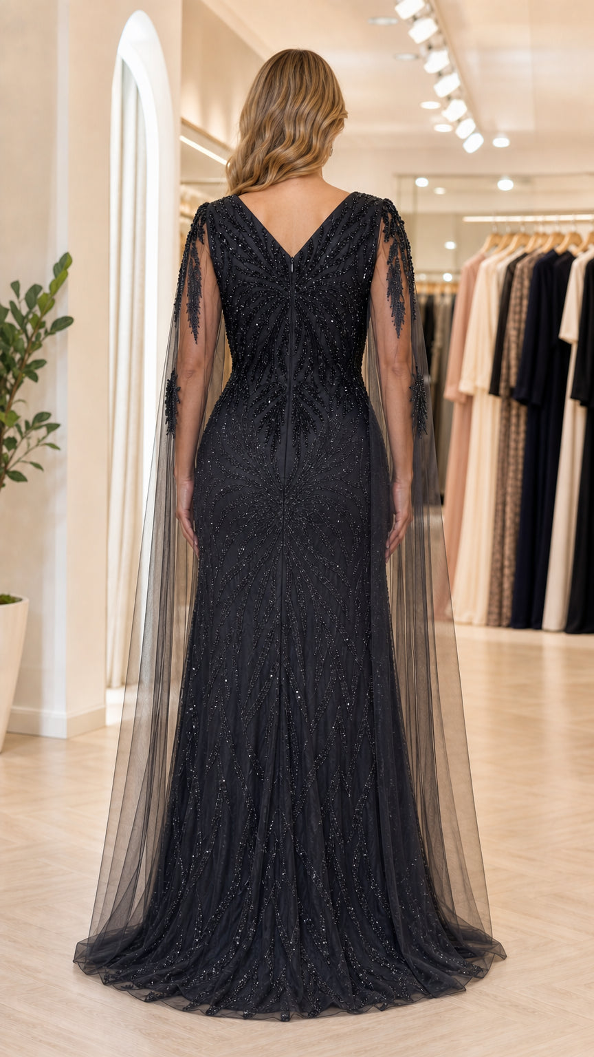 Back view of model showing V-back design and cape overlay on black evening gown