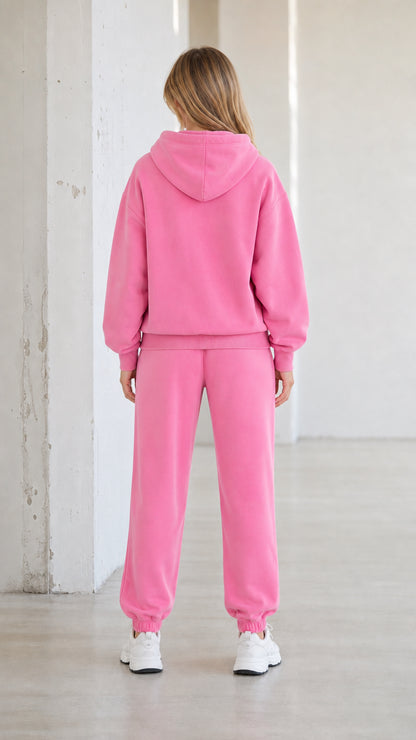 Back view of model wearing pink hooded sweatshirt and jogger pants set