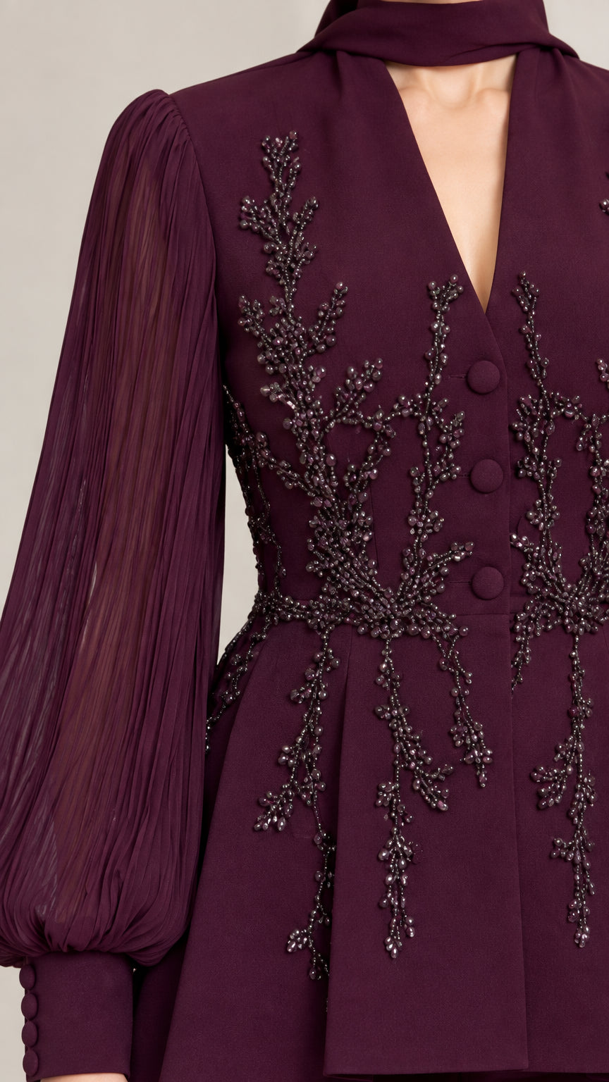 Close-up detail of burgundy beaded embroidery, covered buttons, and sheer sleeves