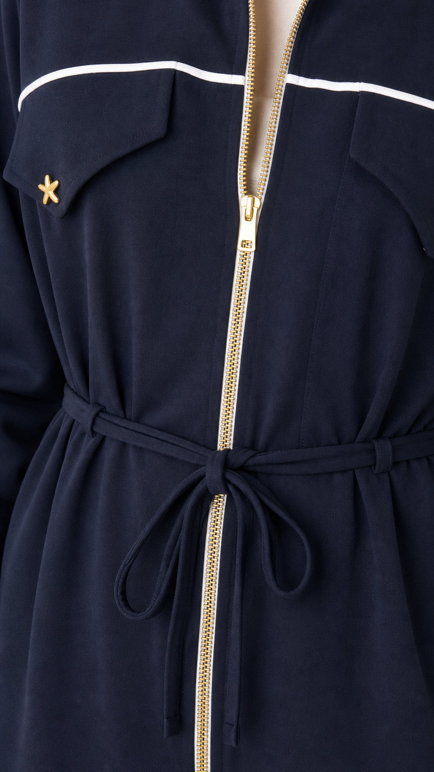 Close-up of gold-tone front zipper, drawstring waist, and chest flap detail on navy jumpsuit