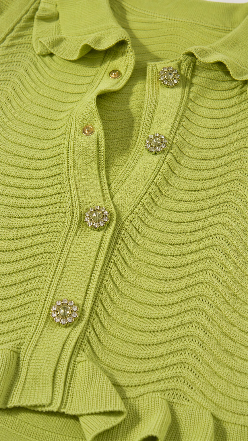 Close-up detail of lime green textured wave knit fabric with ruffle collar and rhinestone buttons
