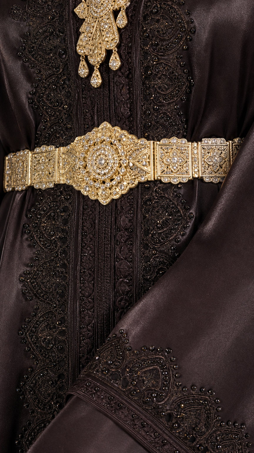 Close-up detail of ornate gold belt and tonal beaded embroidery on dark satin fabric