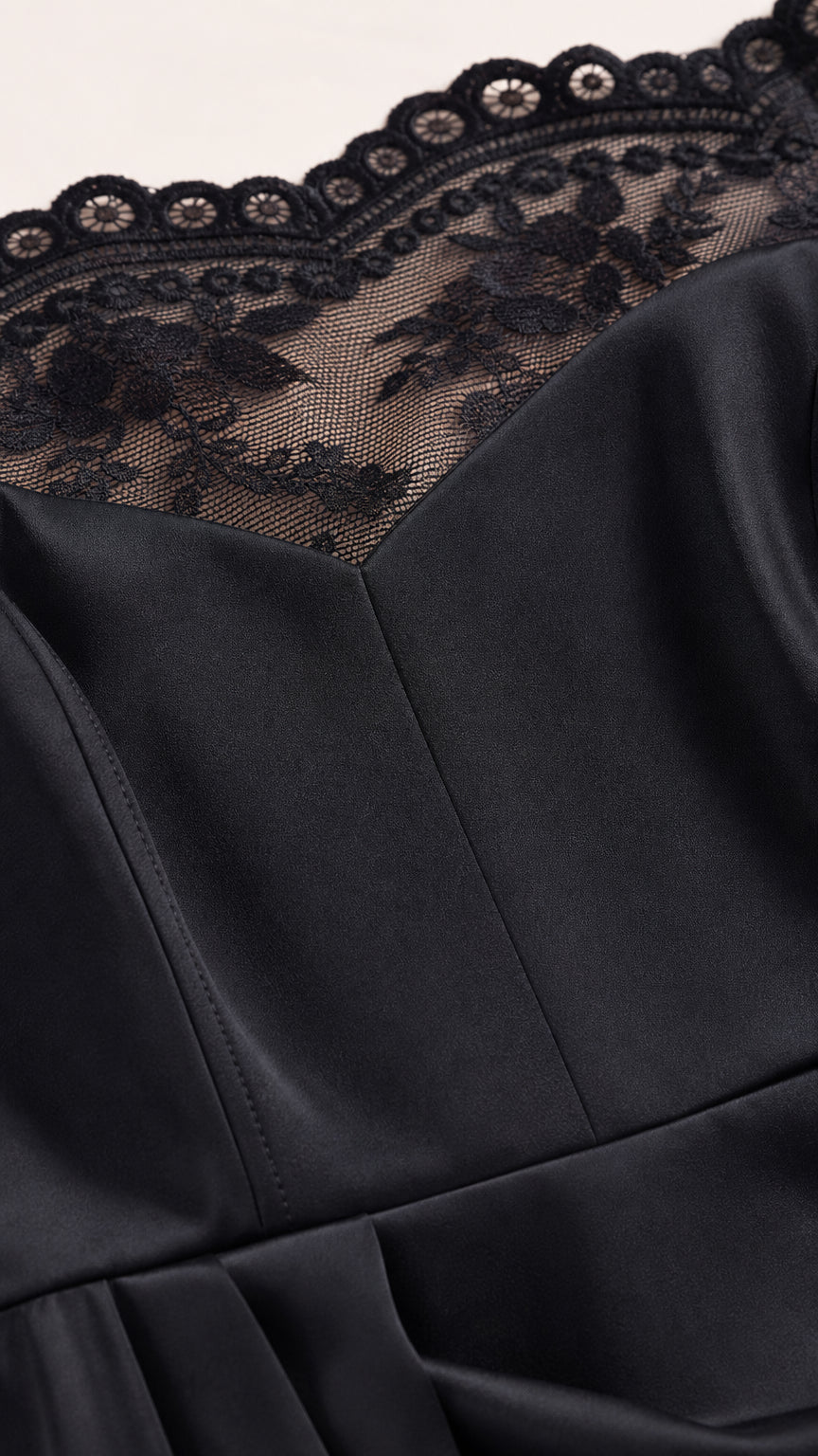 Close-up detail of scalloped black floral lace neckline and structured bodice seams