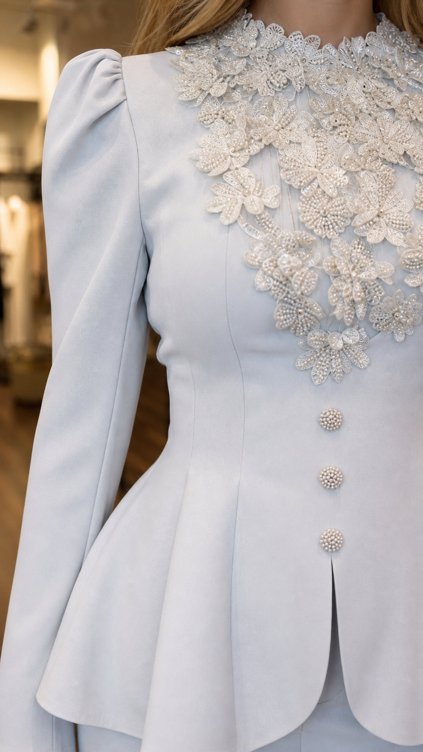 Close up of intricate floral lace applique beadwork and buttons on light blue peplum jacket