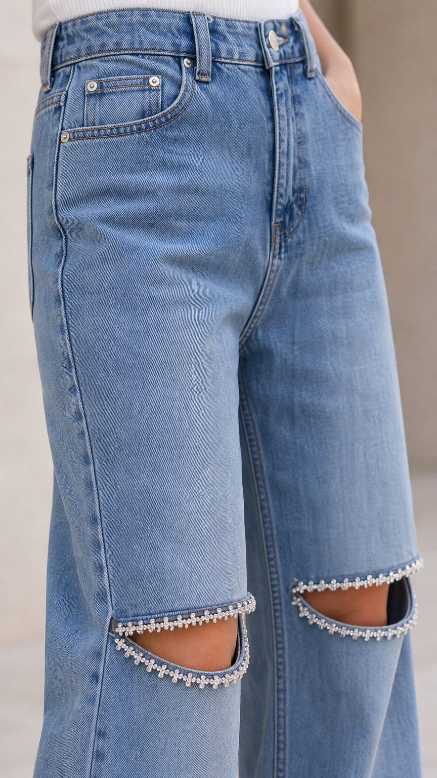 Close-up detail of pocket stitching and pearl-beaded trim along knee cutouts