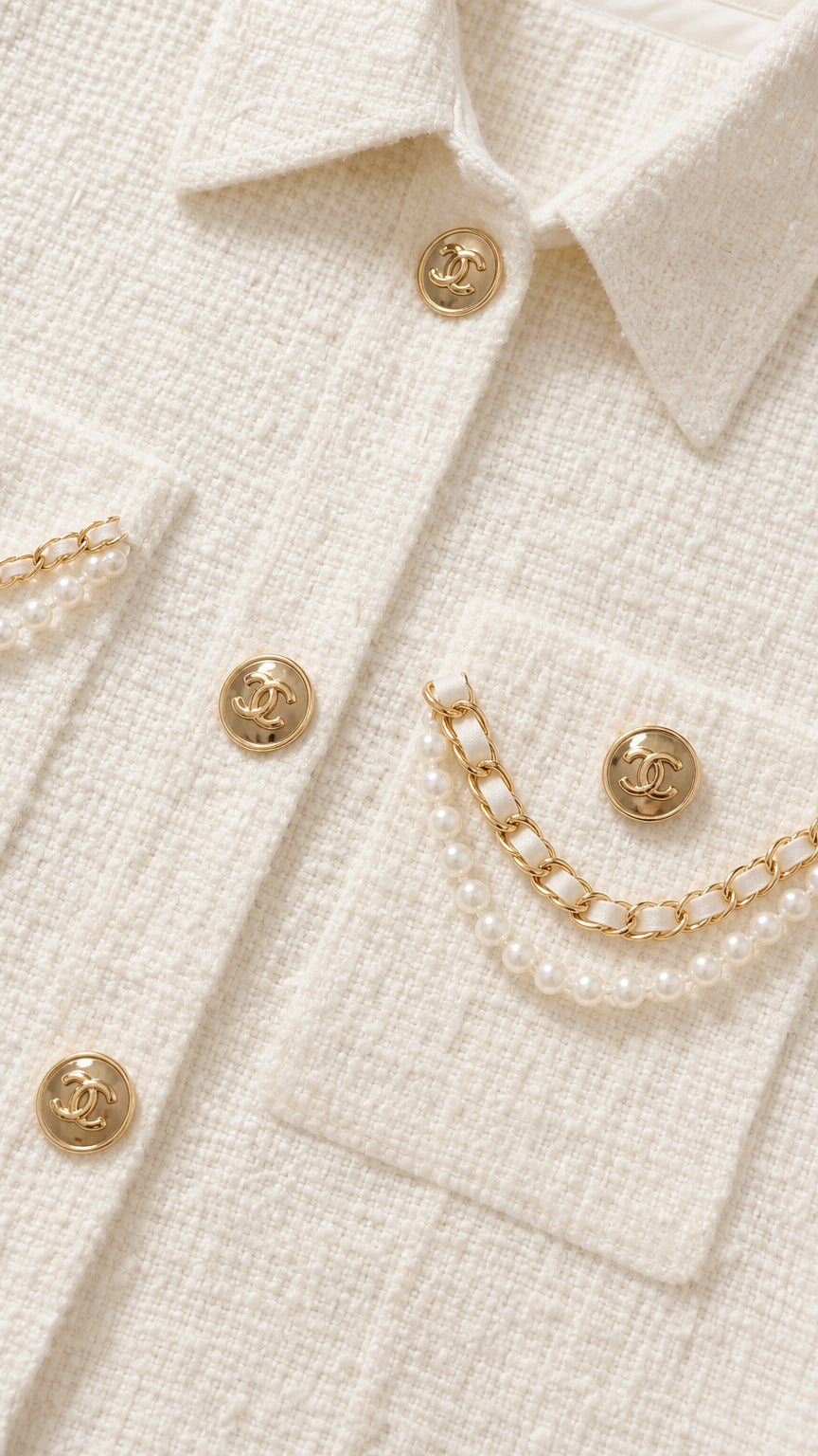 Close-up detail of cream tweed fabric with gold-tone buttons and pearl chain pocket accents