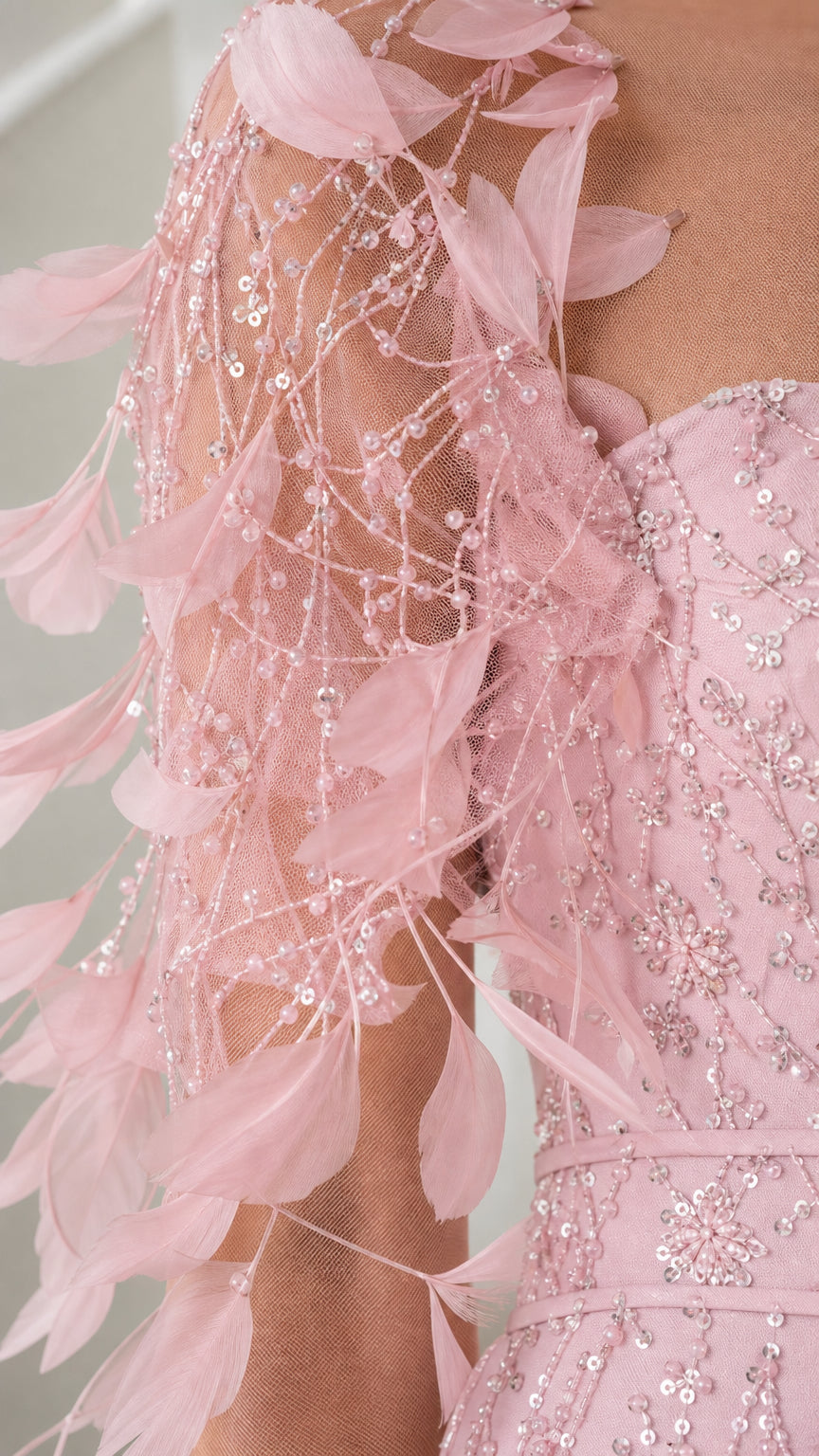 Close-up detail of delicate pink feather appliques, beadwork, and sequin embroidery