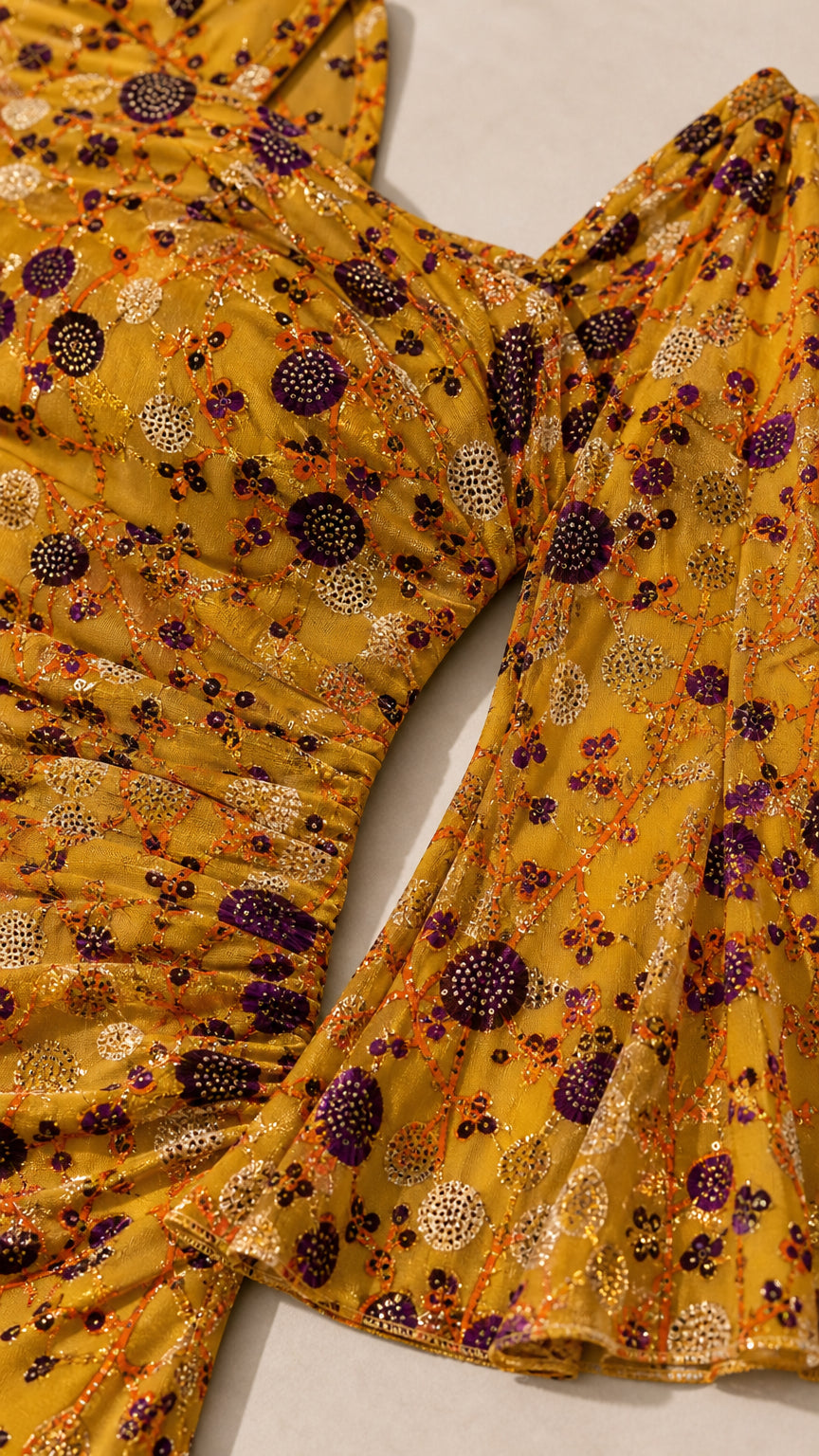 Close-up detail of textured floral fabric with ruched bodice and flared cuff