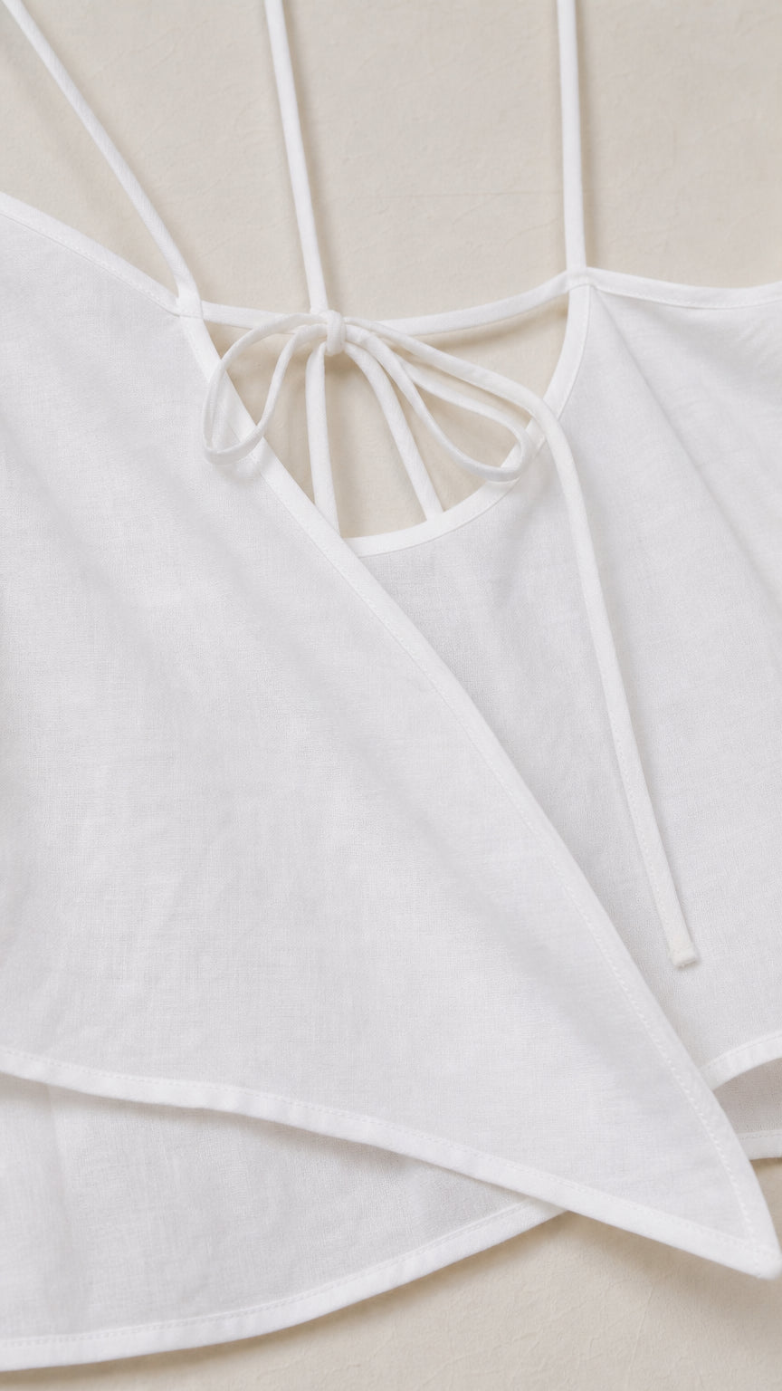 Close-up detail of white spaghetti strap tie-back and pointed handkerchief hem