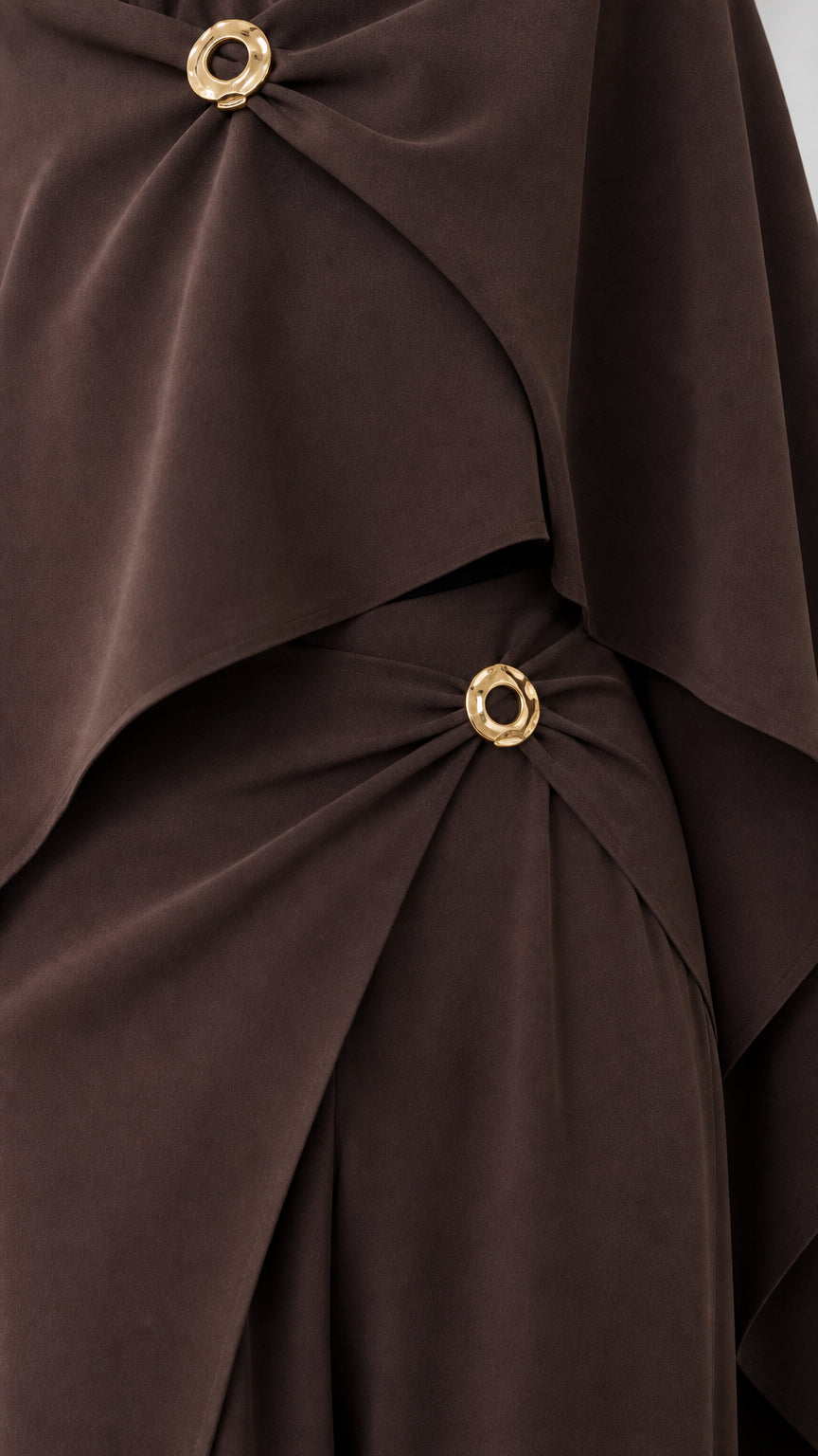 Close-up detail of polished gold-tone ring buckles on draped neckline and waistband