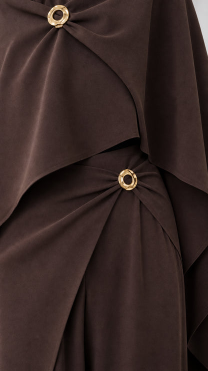 Close-up detail of polished gold-tone ring buckles on draped neckline and waistband