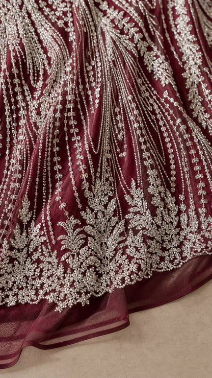 Close-up of intricate beaded sequin embroidery on burgundy tulle fabric
