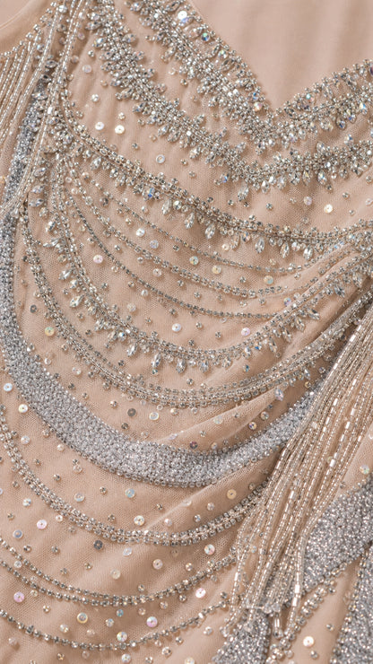 Close-up detail of silver sequin and beaded scalloped embroidery on champagne mesh fabric