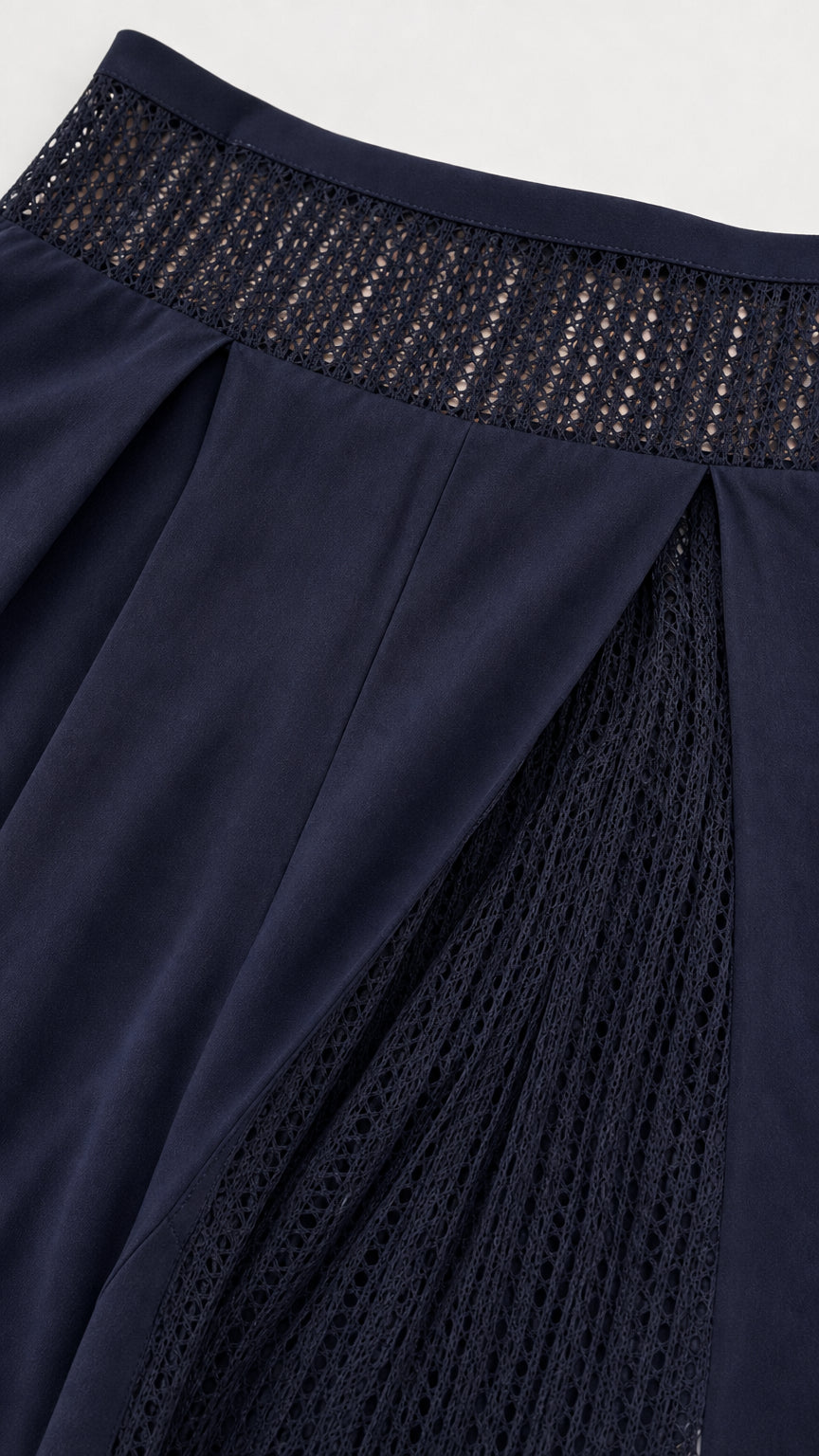 Close-up detail of navy blue crochet waistband and pleated side pants insert