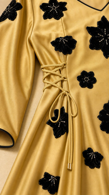 Close-up detail of side lace-up waist tie and textured floral applique on Mustard Gold satin