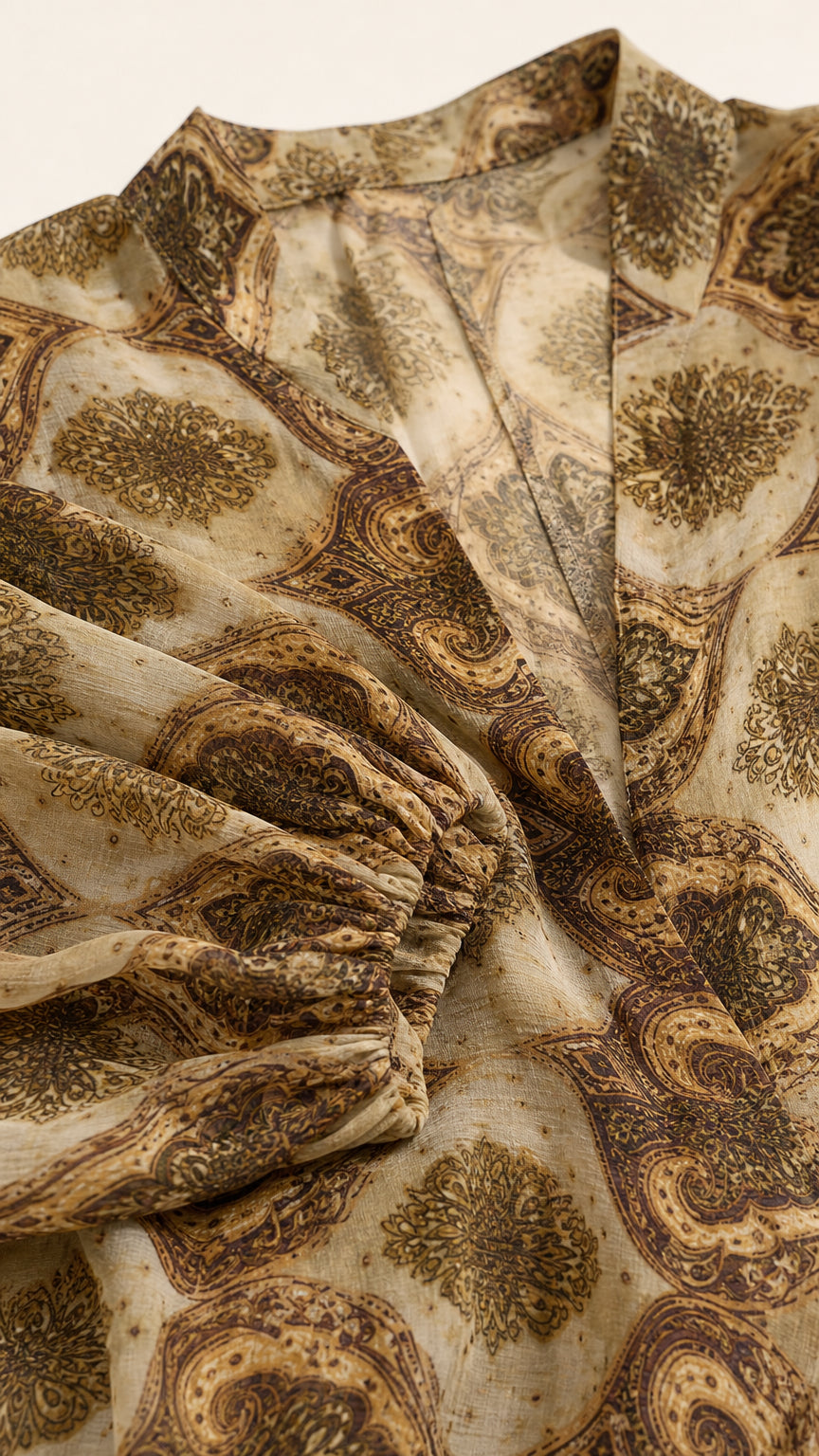 Close-up detail of lightweight fabric, neckline, and elastic sleeve cuff on Camel paisley dress