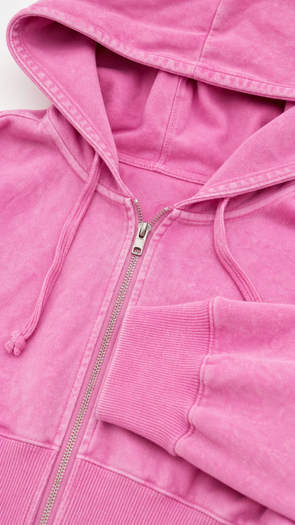Close up detail of washed pink zip up hoodie showing drawstring hood and ribbed cuffs