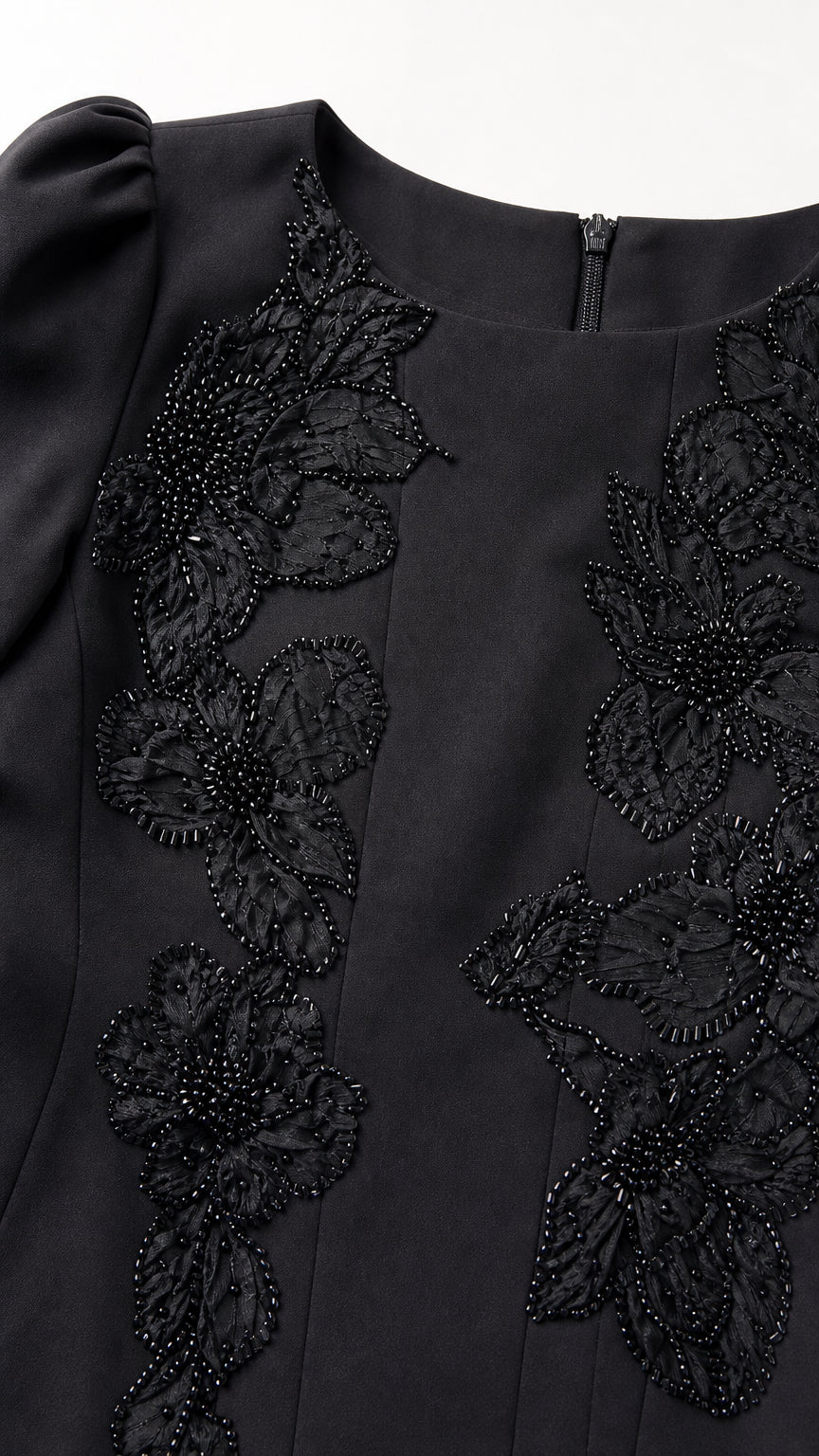 Close-up detail of black floral beadwork and round neckline embroidery