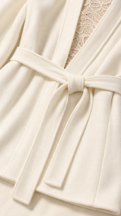 Close-up detail of cream blazer fabric, waist belt knot, and lace underlay