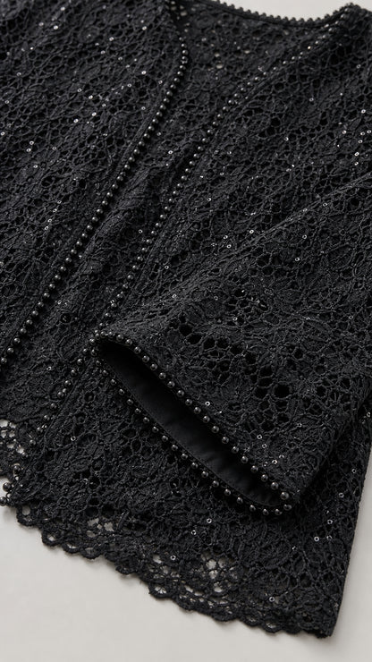 Close-up detail of delicate black floral lace fabric with beaded trim and sequins