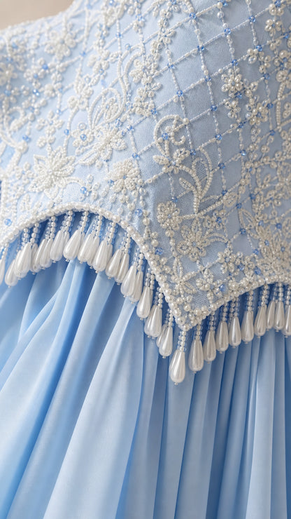 Close-up detail of light blue embroidered bodice with pearl and bead fringe tassels