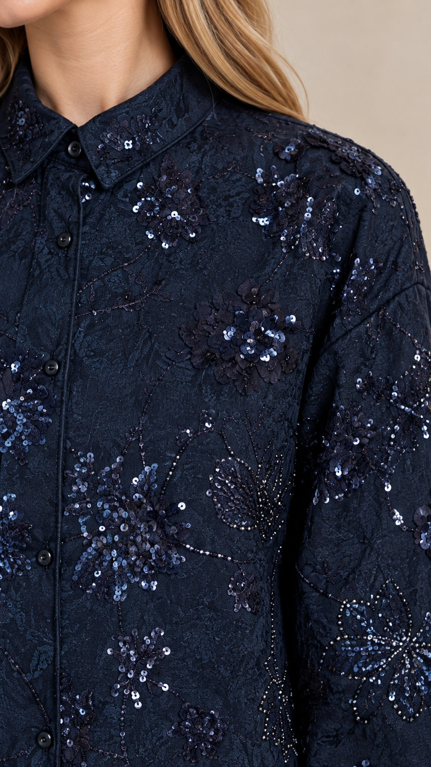 Close-up detail of navy blue textured fabric showing intricate floral embroidery and shimmering sequin accents