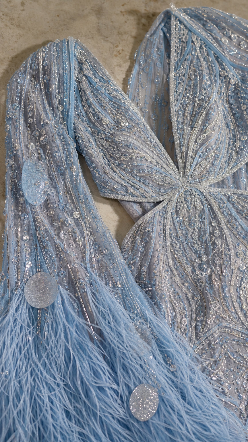 Close-up detail of light blue sequin embroidery, beaded mesh, and feather fringe