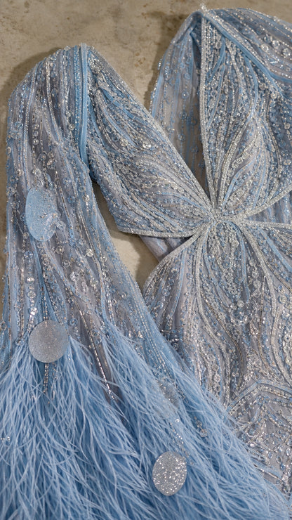 Close-up detail of light blue sequin embroidery, beaded mesh, and feather fringe