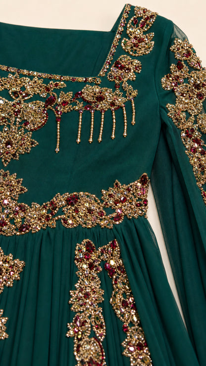 Close-up detail of ornate gold embroidery and beading on dark green chiffon