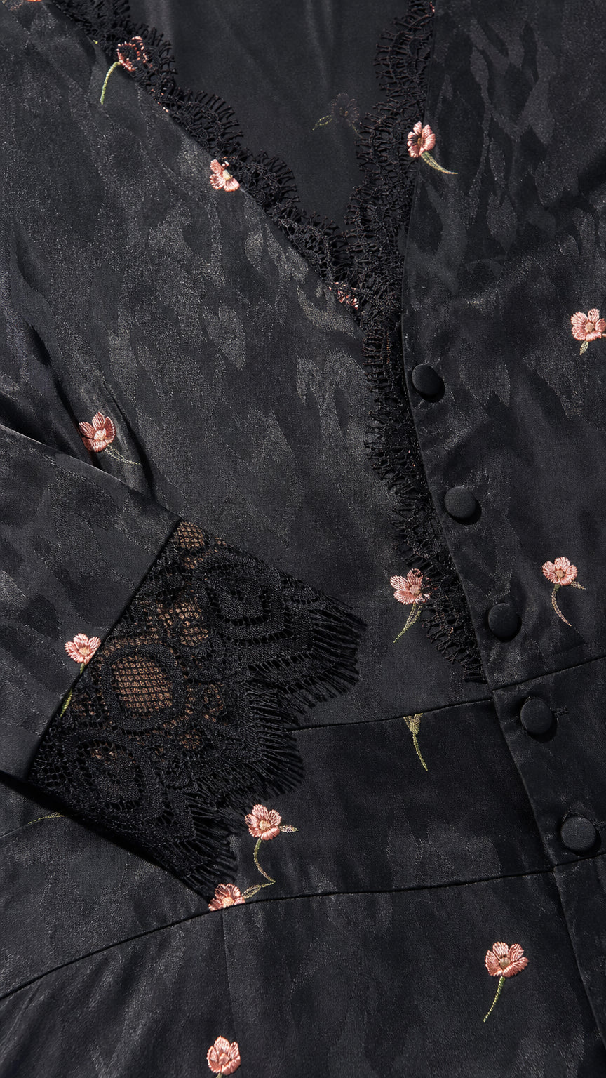 Close-up detail of black floral jacquard fabric, buttons, and lace trim