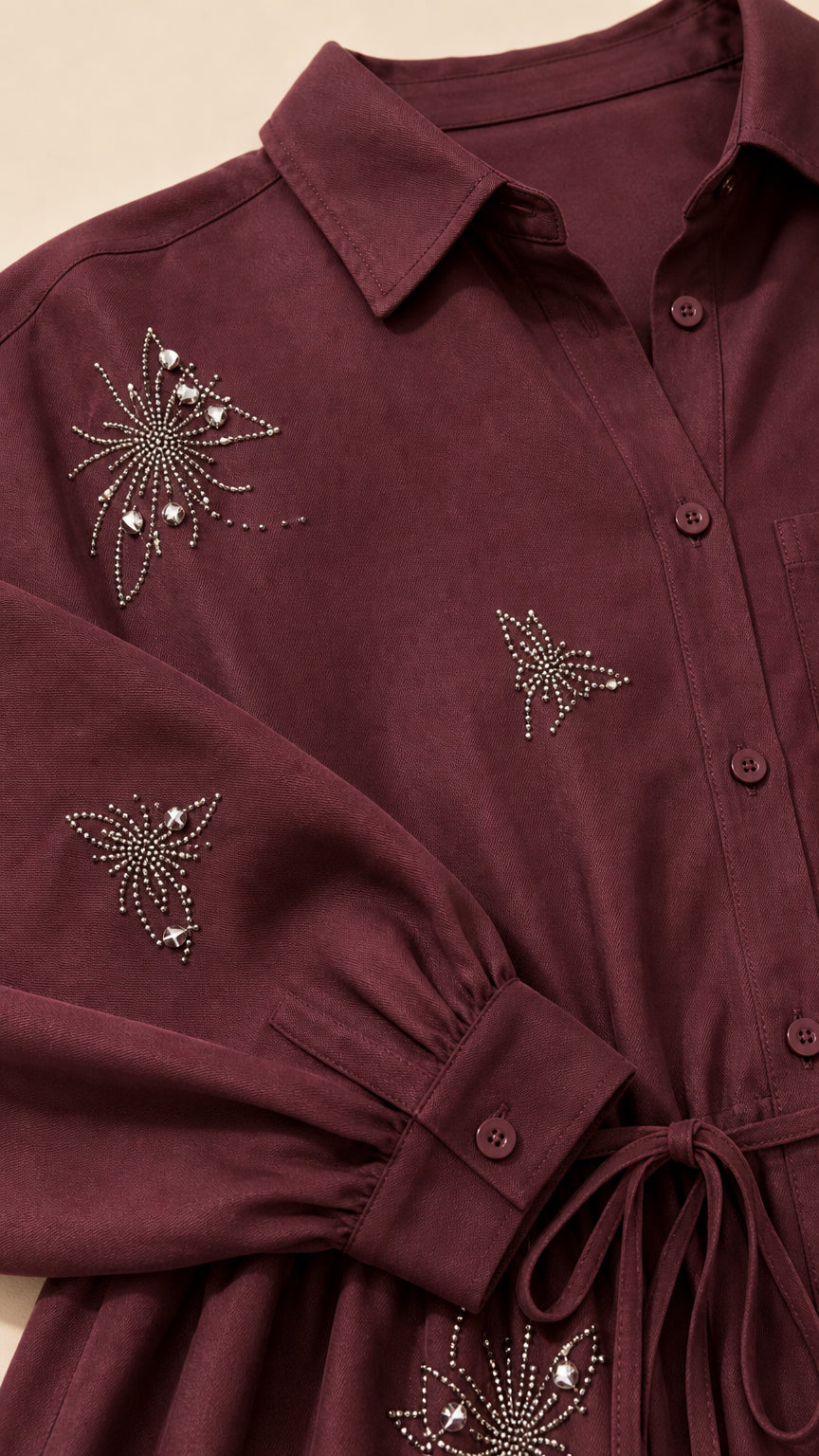 Close-up detail of rhinestone butterfly and starburst embellishments on burgundy collared top