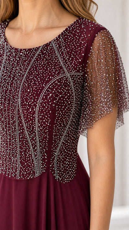 Close-up detail of burgundy sheer flutter sleeve and intricate rhinestone beading on bodice