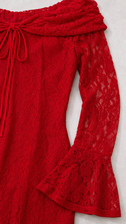 Close-up detail of red floral lace fabric, folded neckline tie, and bell sleeve cuff