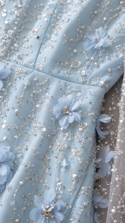 Close-up detail of 3D floral appliqués, sequins, and beading on light blue tulle fabric