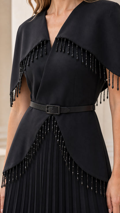 Close-up detail of beaded fringe trim on capelet and belted waist of black evening dress