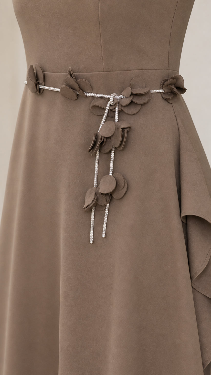 Close-up of waist belt with floral petal appliqué and charm detailing